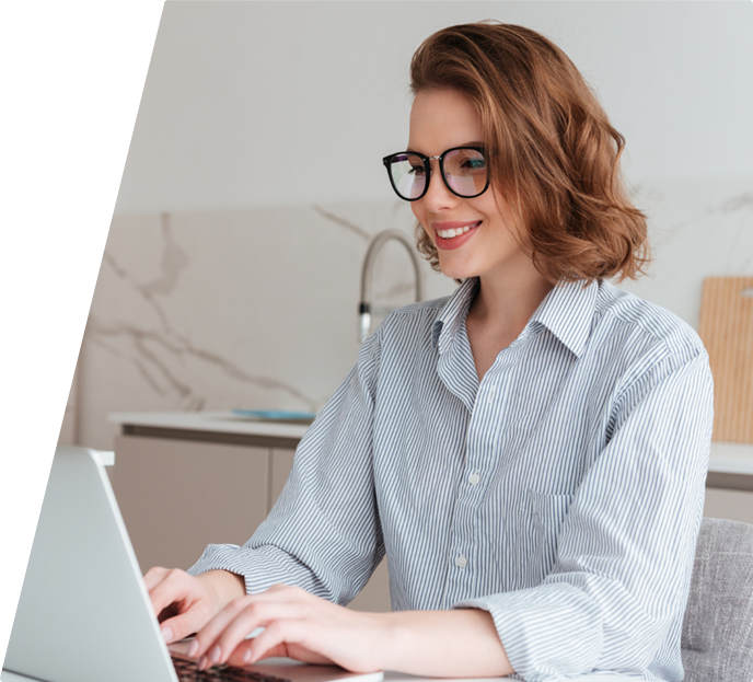 a smiling woman sitting at a laptop typing