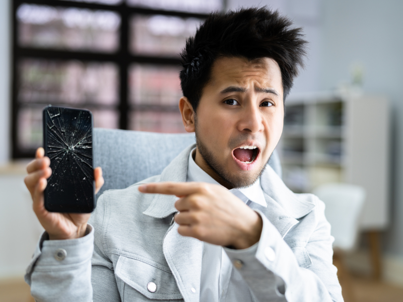 man holding phone with broken screen